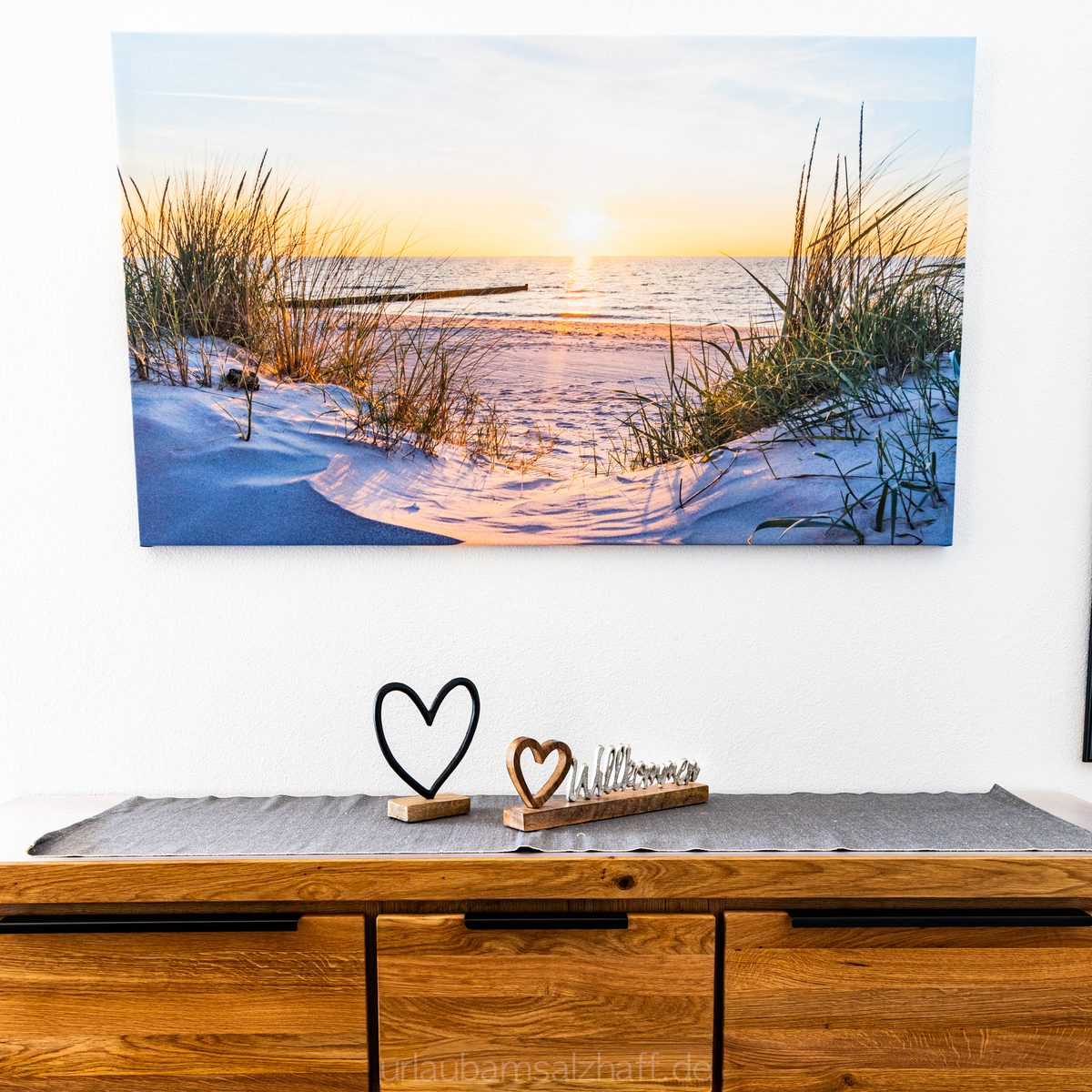 Strandbild über Holzkommode mit herzlichen Deko-Elementen.