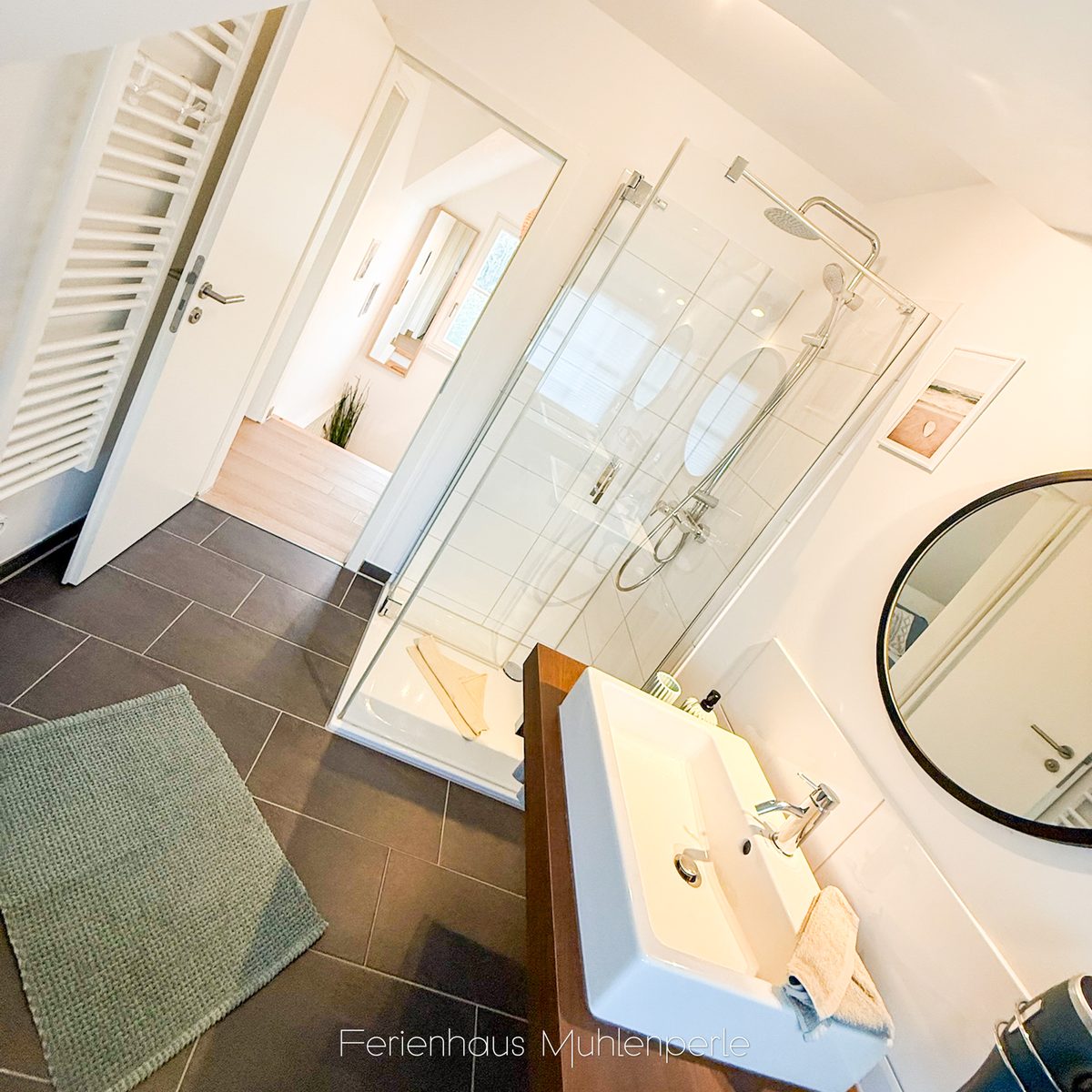 Modernes Badezimmer im Ferienhaus Mühlenperle mit Glasdusche, Waschtisch und Handtuchheizung.