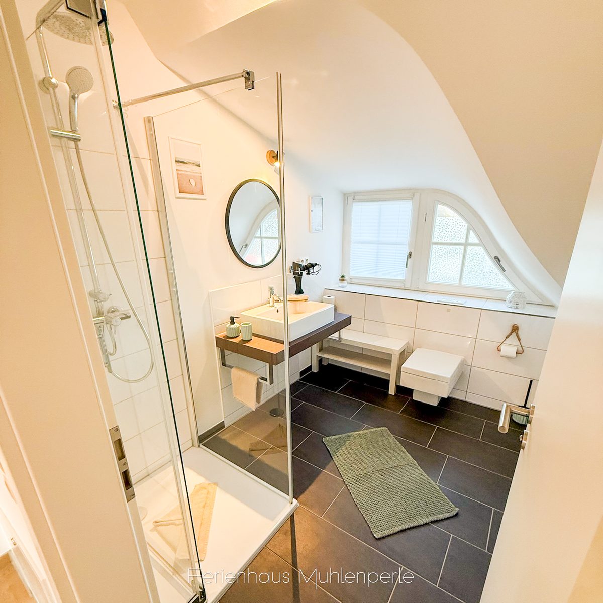 Modernes Badezimmer im Ferienhaus Mühlenperle mit Dusche, Waschtisch und stilvollem Design.