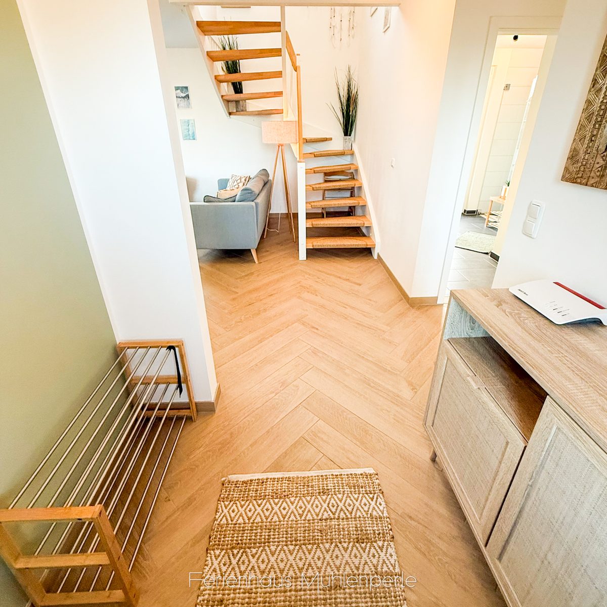 Eingangsbereich im Ferienhaus Mühlenperle mit Blick auf die Holztreppe und den Wohnbereich.