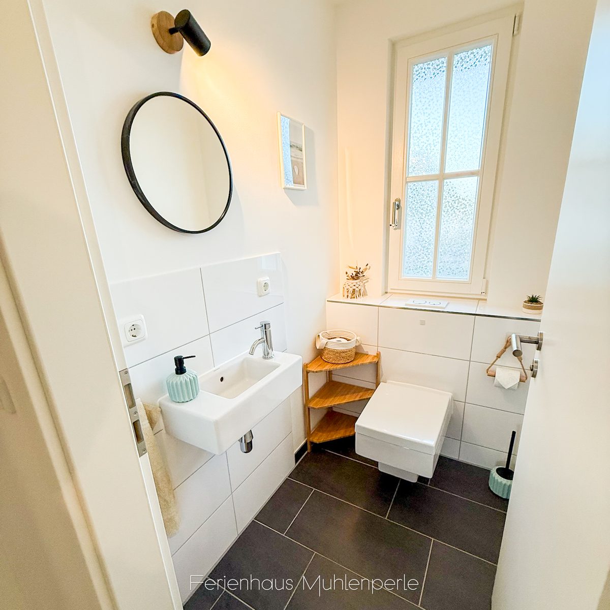 Gästetoilette im Ferienhaus Mühlenperle mit stilvollem Waschtisch, Spiegel und natürlichem Lich