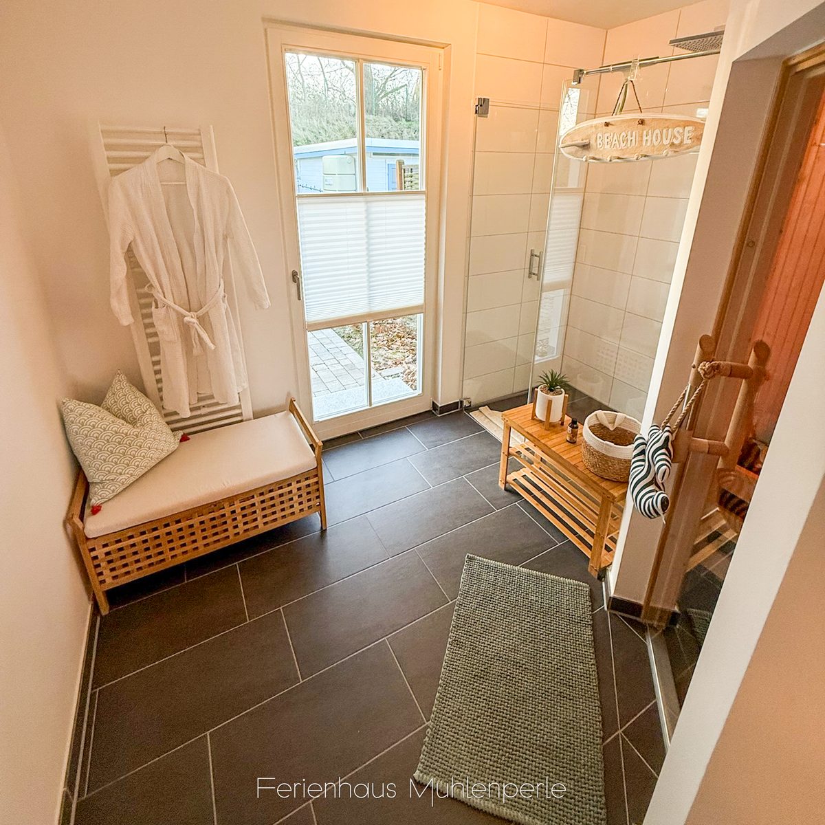 Wellnessbereich im Ferienhaus Mühlenperle mit Dusche, Sauna und direktem Zugang zur Terrasse.