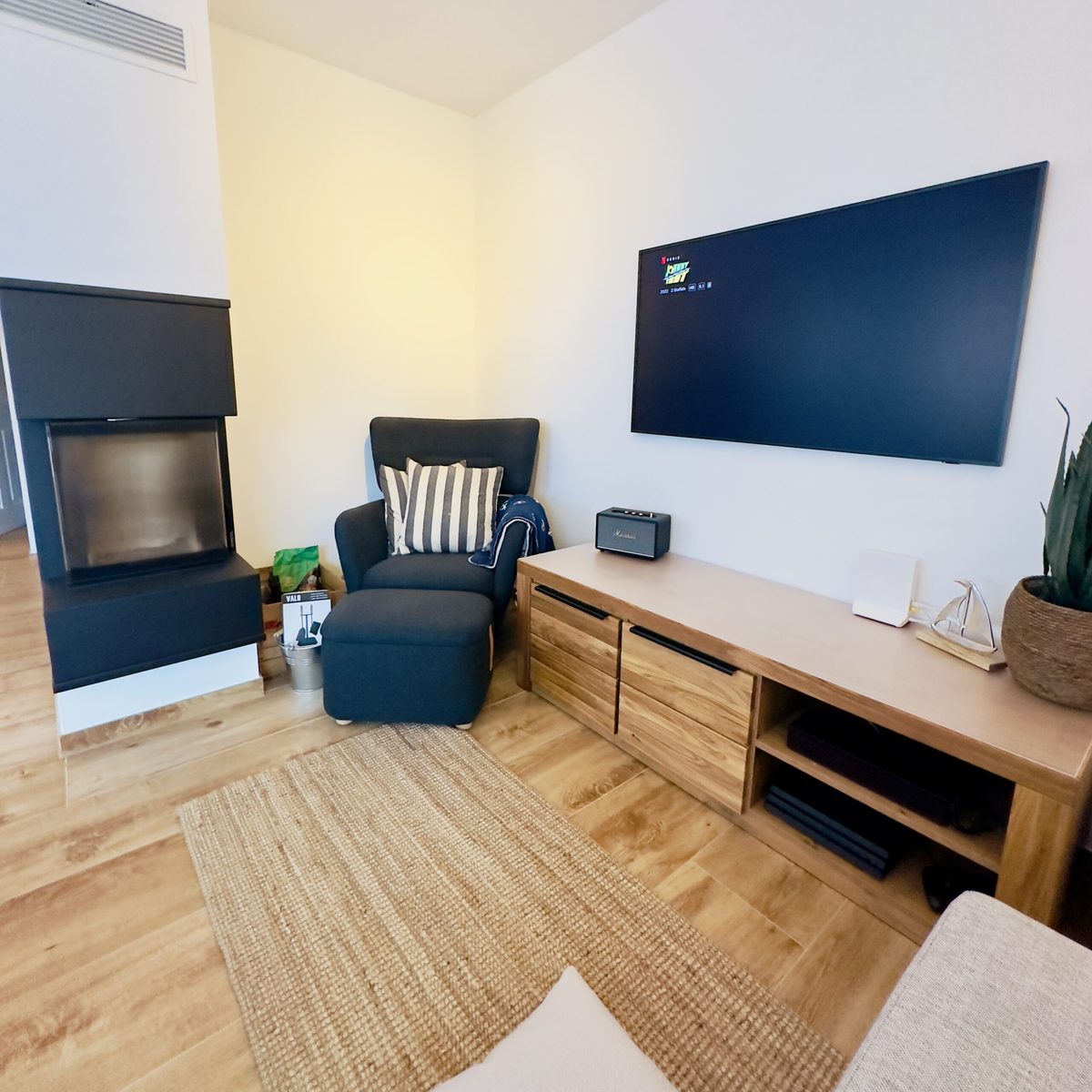 Wohnzimmer mit Kamin im Ferienhaus KiteZeit, gemütlich eingerichtet mit Sofa und TV.