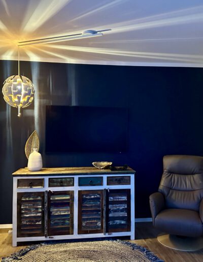 Wohnzimmer bei Dämmerung beleuchtet durch eine kreative Hängelampe, neben einem komfortablen Sessel.