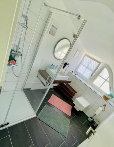Helles, geräumiges Badezimmer mit großer Dusche und modernen Einrichtungsdetails.