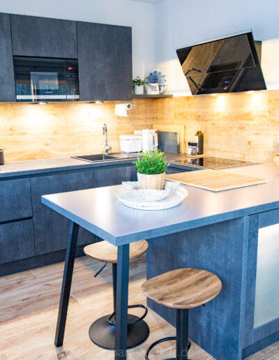 Moderne Küche mit Tresen und Barhockern, beleuchtet durch warme Unterkabinettbeleuchtung.
